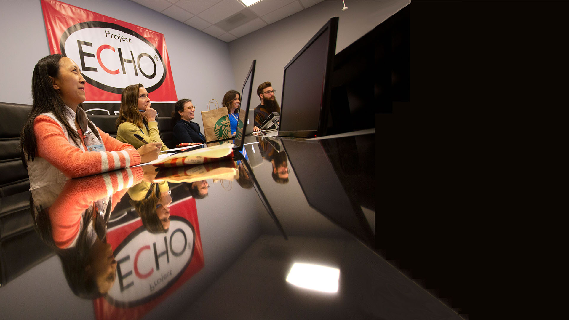 A group of research scientists sitting in front of a conference table with the ECHO logo on the background wall. 